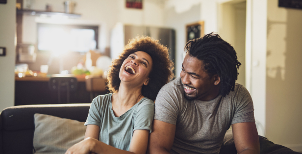 A couple laughing in front of the television.