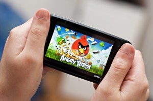 Playing Angry Birds game on a mobile phone.