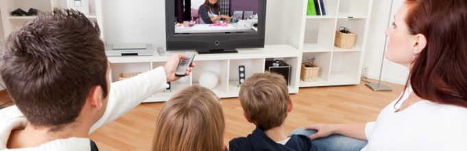 Family sitting in living room watching TV