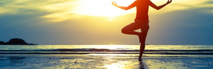 A zen woman doing a yoga pose on the beach