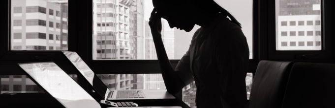 A woman sitting in distress at her office desk