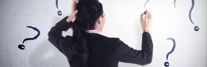Woman writing question marks on whiteboard