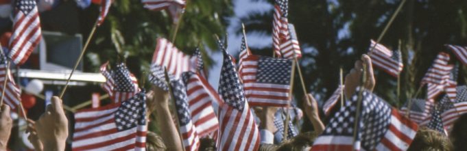 Crowd of people holding up small American flags