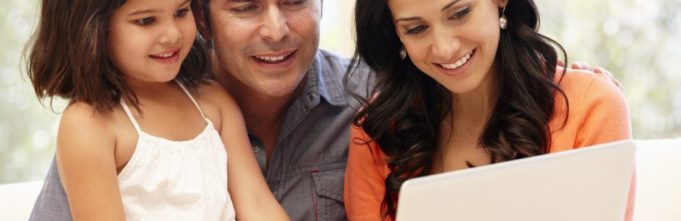 A family sitting together looking at a laptop.