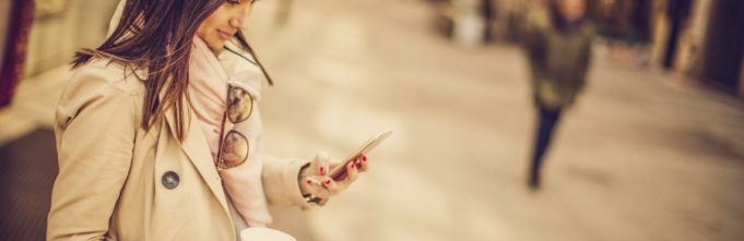 Woman standing on a street looking at her phone