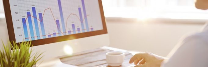 Businessman sitting in front of computer monitor and analyzing data