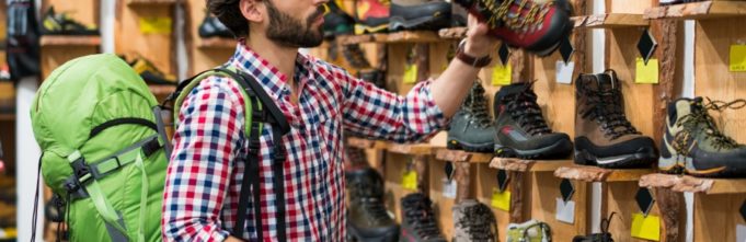 A man in a checkered shirt identifying a pair of hiking boots to purchase.