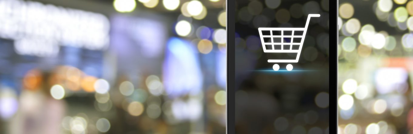 Shopping cart Icon on modern smart phone screen on wooden table over blur light and shadow of mall, Shop online concept.