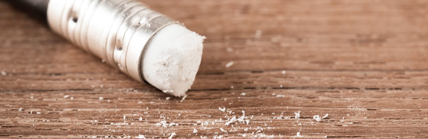 Pencil eraser with pencil shavings on a wooden table.