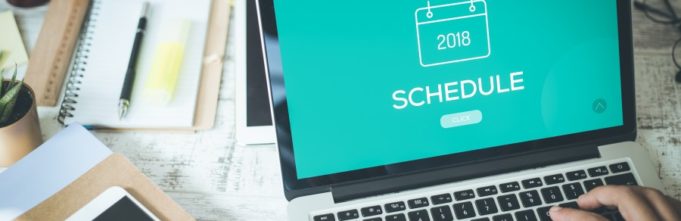 Scheduling on the laptop over a desk of items.