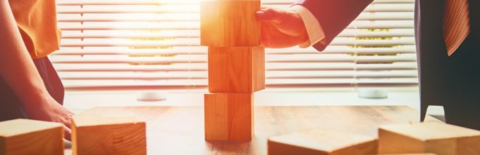 Two business persons plan a project with building blocks.