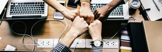 Employees hands all coming together in front of laptops