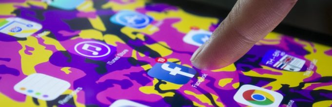 A finger pointing at the Facebook mobile icon