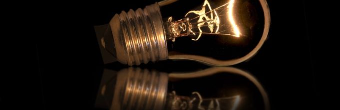 Lightbulb on reflective black surface.