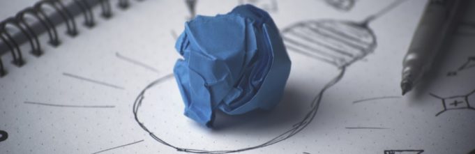 Crumpled piece of paper on top of an illustration of a lightbulb