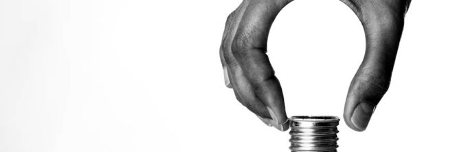 Picture of a hand holding the bottom part of a lightbulb but the white space between his fingers makes the image of the bulb