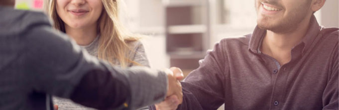 Men shaking hands over coffee among woman.