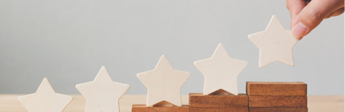 A hand places gold stars on blocks of wood