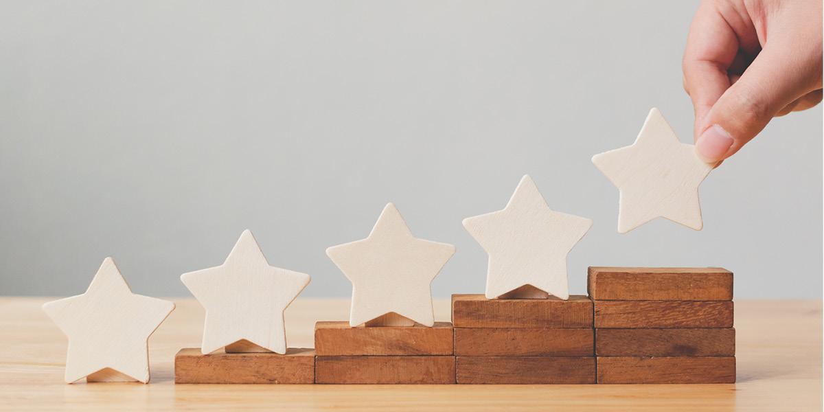 A hand places gold stars on blocks of wood