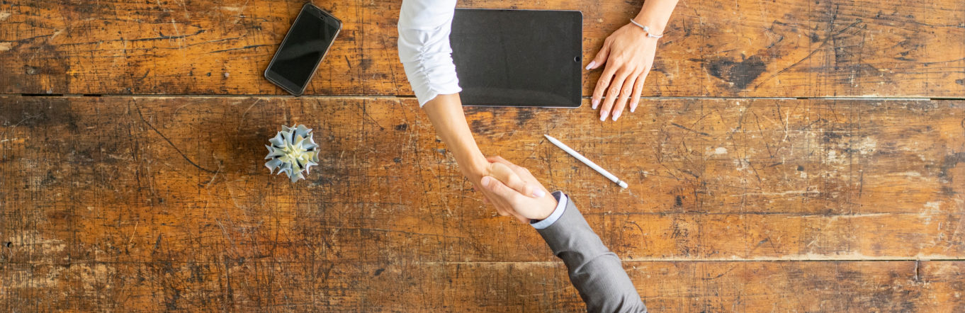 Handshake happening across a wooden table