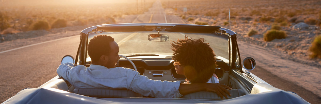 A couple driving a convertible into the sunset