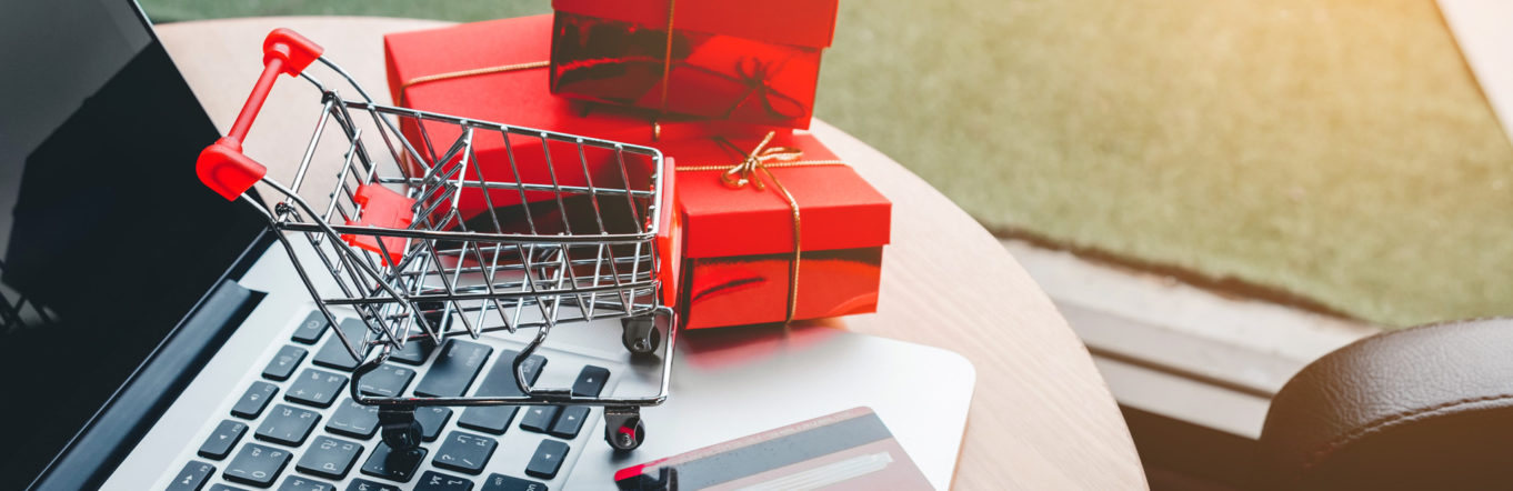 Shopping cart next to red wrapped presents on a laptop