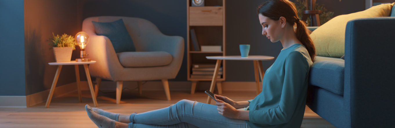 Young woman sitting on the floor watching a Facebook video ad on her tablet