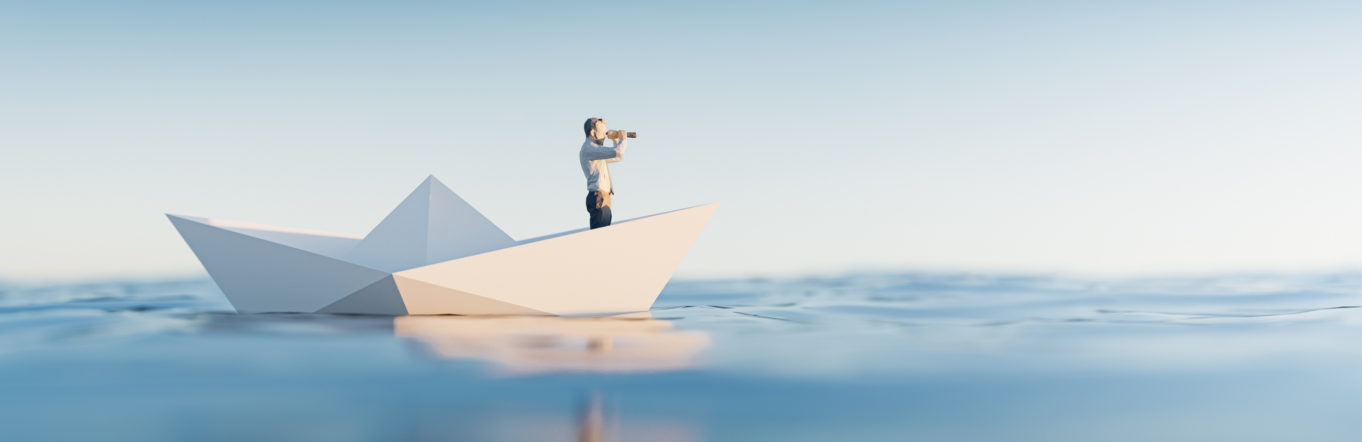 Man floating on a paper boat looking towards the horizon